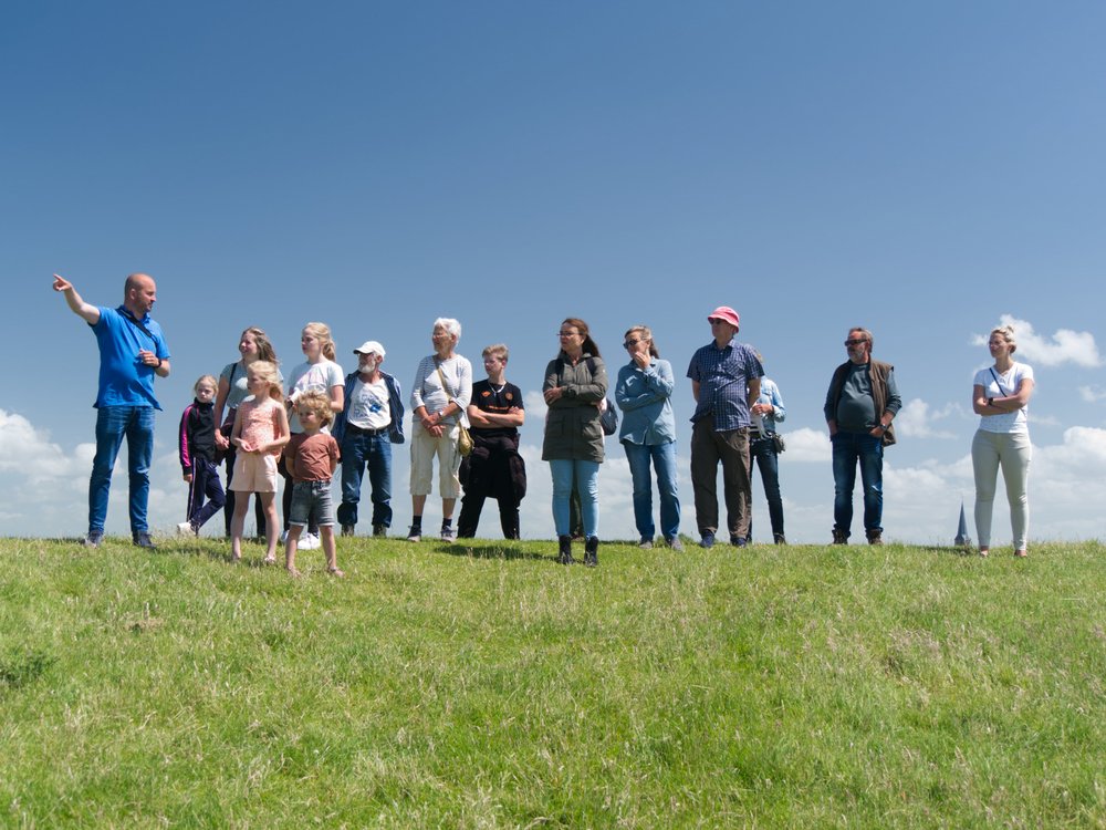 
    
            A group of people is standing on a dyke. The person on the left is explaining something...        
        
